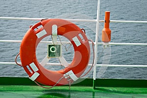 Buoy or lifebuoy ring on shipboard in evening sea. Flotation device on ship side on seascape. Safety, rescue, life preserver.