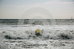 Buoy in the sea waves with foam. Empty beach. Summer vacations travel. Stormy ocean