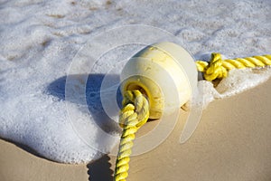Buoy on a yellow rope lying on the wet sand