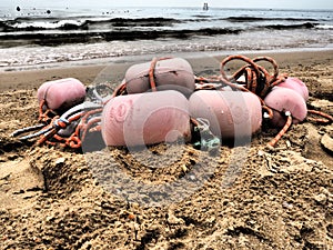 Buoys in the sand. A beach with wet coarse quartz sand. Tangled ropes and plastic buoys left on the shore. Safety