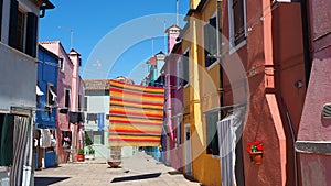 Burano, Venice, Italy. Street with colorful houses and colored tablecloth spread out to dry