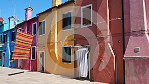 Burano, Venice, Italy. Street with colorful houses and colored tablecloth spread out to dry