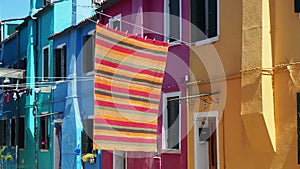 Burano, Venice, Italy. Street with colorful houses and colored tablecloth spread out to dry