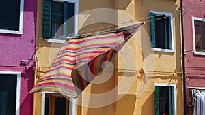 Burano, Venice, Italy. Street with colorful houses and colored tablecloth spread out to dry