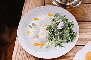 A Buratto ball and arugula raab salad on a plate. A delicious ball of Italian cheese photo