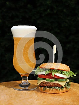 Glass of beer with burger on wooden table with dakt  background