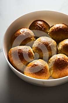 Burger Buns or mini buns in the round baking pan. Very soft Freshly Baked Homemade, buttered. White marble background