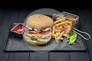 Burger with chicken cutlet and french fries on a dark background