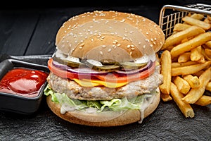 Burger with chicken cutlet and french fries on a dark background