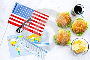 Burger, chips, map, tickets and usa flag for gastronomical tourism to America on marble background top view