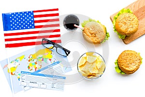 Burger, chips, map, tickets and usa flag for gastronomical tourism to America on white background top view