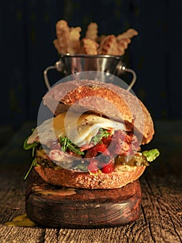 Burger with chopped meat, egg and arugula on a wooden table