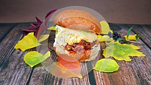 Burger and french fries on wooden background with autumn leaves,fast food concept, take away food concept, season sales