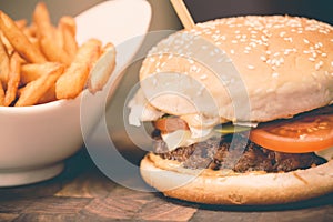 Burger with fresh tomato, cheese, meat and french fries. Selective focus