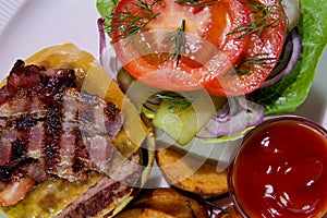 Burger with fried bacon, french fries, vegetables and ketchup on a white plate.View from above.Close-up.Binge eating