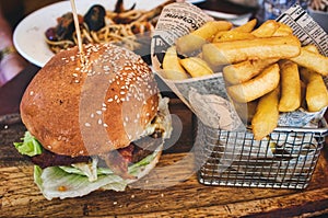 Burger and fries / chips in a basket on a wooden board in a restaurant