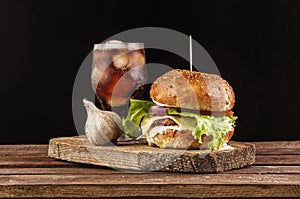 Burger with garlic and cola on wooden cutting board with copyspace