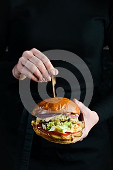 Burger in the hands of the chef. Fast food concept.
