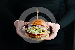 Burger in the hands of the chef. Fast food concept.