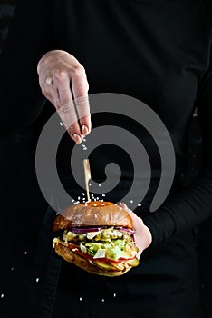 Burger in the hands of the chef. Fast food concept.