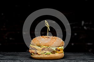 Burger with a latch on a wooden board on a black background