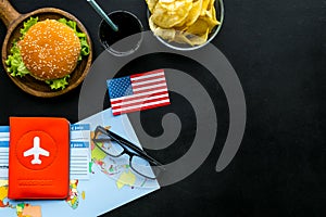 Burger, map, tickets, passport and usa flag for gastronomical tourism to America on black background top view copyspace