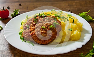 Burger with mashed potatoes in white plate on wooden background