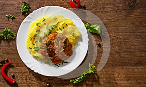 Burger with mashed potatoes in white plate on wooden background