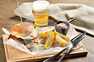 Burger, mexican potatoes and ketchup on wooden board