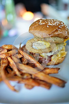 Burger with onion rings eggs bacon and sweet potatoe fries