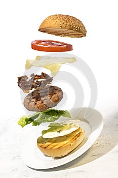 Burger preparation sliced  ingredients levitating on white background
