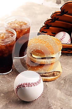 Burger on the table with softdrink cola. Baseball party food with balls for the playoffs