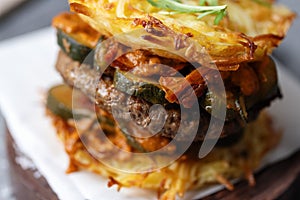 Burger with vegetables and potato patty on table