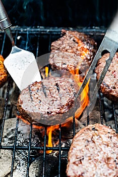 Burgers are cooking on grill with open flames