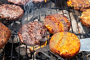 Burgers are cooking on grill with open flames