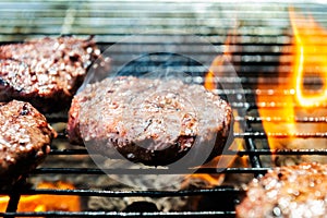 Burgers are cooking on grill with open flames