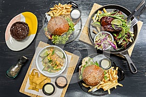 Burgersm french fries, ceviche, ribs and muffin on a wooden table