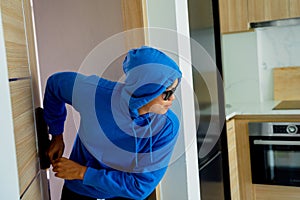 Burglar breaking in an apartment to steal something.