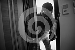 Burglar breaking in a house with crowbar