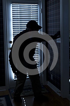 Burglar Breaking In To Home At Night Through Back