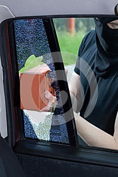 A burglar breaks a window in the car