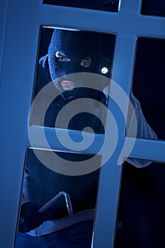 Burglar with crowbar breaking into a house