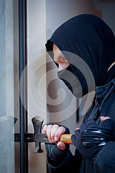 Burglar with crowbar to break door to enter the house