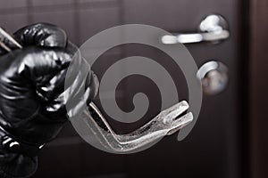 Burglar hand holding crowbar break opening door photo