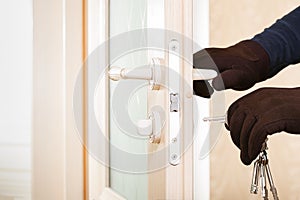 Burglar with lock picking tools breaking and entering into a house.