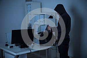 Burglar Putting Laptop Into Bag At Desk In Office