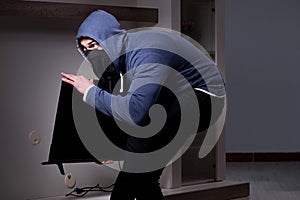 The burglar thief stealing tv from apartment house