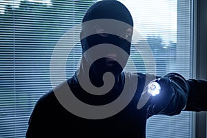 Burglar wearing a balaclava holding a flashlight