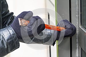 Burglar wearing leather coat breaking in a house