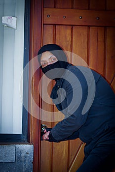 Burglar with wearing a mask trying to enter the house